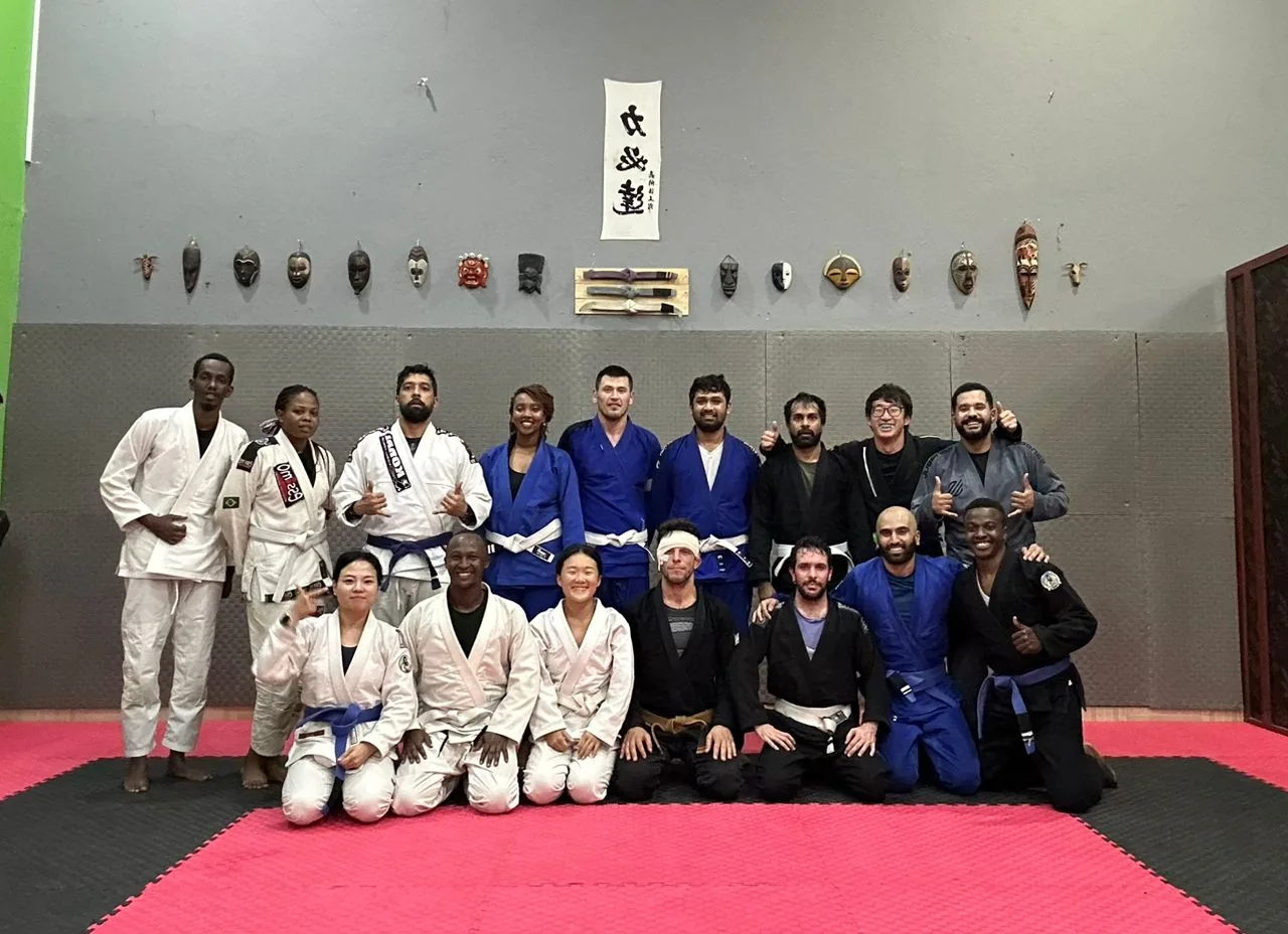 Kigali BJJ students posing together on the red mats